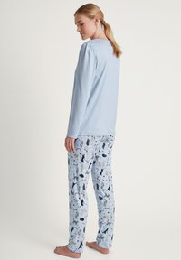 Lichtblauwe longsleeve top van zacht materiaal met elastische manchetten, gecombineerd met gestreepte pyjamabroek met verschillende dierillustraties.