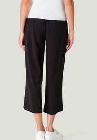 Zwarte cropped broek van zachte stof, met een ontspannen pasvorm en een wijde pijp, een gladde textuur en een eenvoudige afwerking van de zoom.