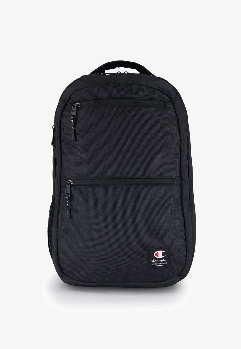 Czarny plecak z teksturowanej tkaniny. Posiada dwie przednie kieszenie zapinane na zamek oraz uchwyt na górze. Zawiera łatę z logo na dolnej części przodu.