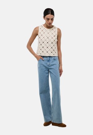 Débardeur en crème au crochet avec un motif floral, associé à un jean large bleu clair et des chaussures marron. Design simple, texturé et décontracté.