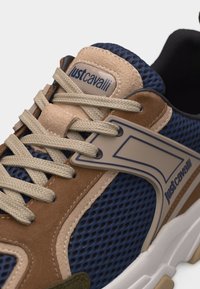 Αθλητικό παπούτσι με μπεζ κορδόνια, καφέ σουέντ επενδύσεις, πάνελς από δίχτυ σε ναυτικό μπλε και λογότυπο Just Cavalli στη γλώσσα και στο πλάι.