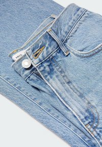 Jean en denim bleu clair avec braguette zippée, bouton en métal et surpiqûres jaunes contrastantes. Comprend une étiquette et des passants pour ceinture.