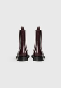 Bottines en cuir bourgogne avec une finition lisse, des panneaux latéraux élastiques et des tirettes, dotées d'une semelle noire et de détails de couture minimaux.