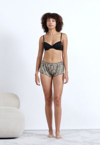 Soutien-gorge noir à armatures associé à un short imprimé léopard. Le short dispose d'une taille élastique et d'une coupe décontractée, fabriqué en tissu léger.