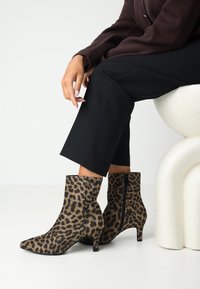 Stivali alla caviglia con stampa leopardata, dalla forma elegante, textures morbida, punta affusolata e tacco medio, arricchiti da un dettaglio con zip laterale.