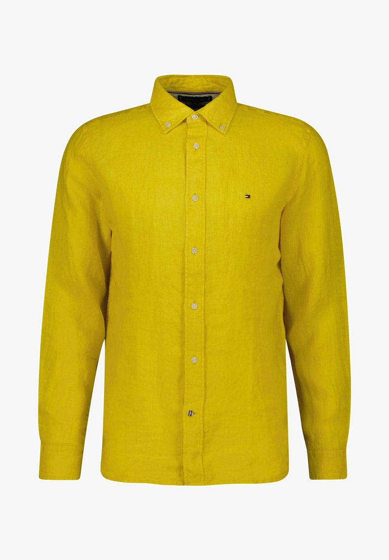Chemise jaune à manches longues avec col, petit logo sur la poitrine et boutons blancs, présentée sur un fond uni.
