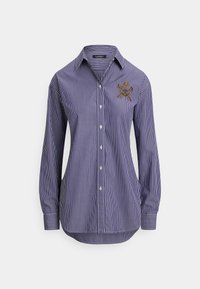 Modrá a biela pruhovaná košeľa s dlhým rukávom, golierom na zapínanie na gombíky a vyšívaným detailom na ľavej strane hrudníka. Má zakrivený lem.