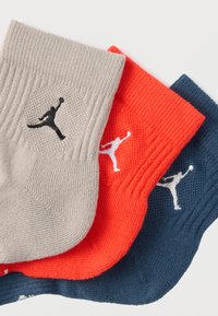 Kolm paari meessokke beežis, oranžis ja tumesinis, millel on soonilised varreotsad ja tikitud Jumpmani logod mustas või valges.