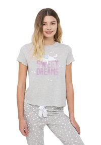 Maglietta da pigiama grigia a maniche corte con la scritta "SWEET DREAMS" in caratteri luccicanti e una grafica di un gatto. Abbinata a pantaloni grigi chiari con motivi a cuore bianchi.