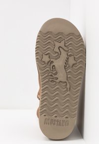 Sole boty v béžové gumě, s vlnitým vzorem, vystouplým designem jednorožce a s názvem značky "MUSTANG" vyraženým na spodní straně.
