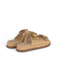 Sandalias de paja trenzada en color tostado, con dos grandes lazos decorativos y suelas planas, que ofrecen un diseño de punta abierta y una superficie texturizada.