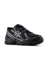Pantoful sportiv negru cu un superior din plasă, talpă din cauciuc și accente reflective. Logo notabil pe lateral și detalii texturate pe întreaga suprafață.