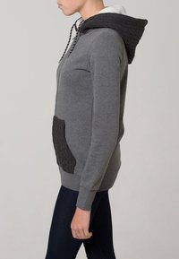 Felpa grigia con tasca a lavorazione a trecce, dotata di cappuccio foderato in pile bianco e chiusura con coulisse. Maniche lunghe, forma aderente.