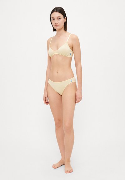 Dzeltena ribota bikini komplekts ar triānglu topu un atbilstošām apakšdaļām. Satur regulējamas siksnas un mazu logo uz sāna. Gluda tekstūra.