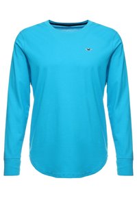 Long-sleeve, round-neck T-shirt in bright turquoise cotton. Features a small logo on the chest and a curved hem for a relaxed fit.