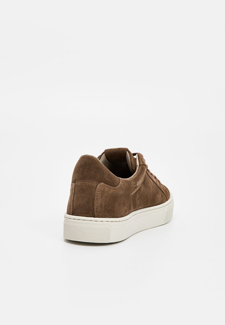 Braune Wildleder-Sneaker mit einer weißen Gummisohle, runder Zehenpartie, Schnürung an der Vorderseite und strukturierten Akzenten an der Fersenpartie.