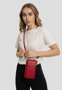 Bolso bandolera de imitación cuero rojo con superficie texturizada, forma rectangular, cierre de cremallera y correa desmontable. Compartimento en la parte delantera.