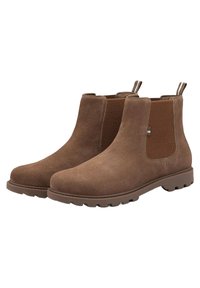 Botas Chelsea de ante marrón con paneles laterales elásticos y lengüetas. Suela de goma gruesa y detalles texturizados en los laterales.