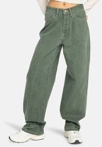 Jean large vert en denim, avec une taille haute, des coutures visibles et des poches avant. Texture lisse avec une coupe décontractée.