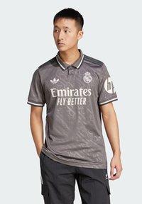 Polo grigio con texture a motivi, dotato di colletto, tre bottoni e logo Emirates e Adidas sul davanti e sulla manica.