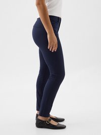 Navy blue stretchy pants with a fitted design and side pockets, paired with flat black shoes featuring a buckle detail.