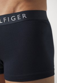 Boxers en coton marine avec une coupe ajustée, dotés d'un logo blanc contrastant sur la taille élastique. Texture lisse, longueur moyenne.