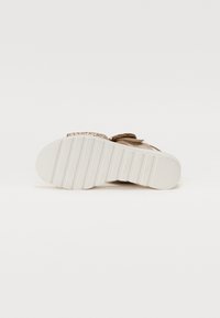 Brune sandaler med en teksturert overdel og en tykk hvit såle. Remmene er justerbare med en metallakcent, som har et rillet mønster.