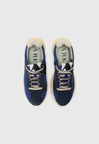 Blue athletic sneakers with varying textures, featuring a beige tongue and laces, black accents, and a cream rubber sole.