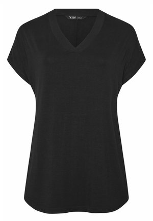 Camiseta negra de manga corta y cuello en V para mujer, de corte holgado y dobladillo curvado, hecha de tela suave, con etiqueta visible en el interior del cuello que dice "YOURS".