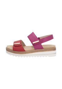 Sandale bicolore avec des brides en cuir rouge et rose, semelle plate avec une plateforme beige texturée et des accents de quincaillerie décoratifs.