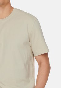 Beige kortærmet t-shirt lavet af blødt bomuld; rund hals design med en glat tekstur og minimale synsømme.