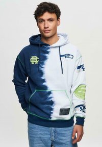 Mörkblå och vit tie-dye hoodie med Seahawks-logotyp, gröna detaljer och känguruficka. Mjuk material med justerbara snoddar.