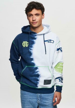 Hoodie bleu marine et blanc en tie-dye avec le logo des Seahawks, accents verts et poche kangourou. Matière douce avec cordons de serrage ajustables.