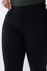 Jeans negros de tiro alto con una textura suave, que cuentan con dos bolsillos frontales y un cierre de doble botón. Diseño simple y ajustado.