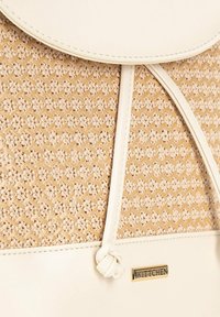 Sac en tissu beige avec une surface texturée, rehaussé d'un empiècement en cuir blanc lisse et d'un logo doré "Wittchen". Dispose d'une fermeture à rabat arrondi.