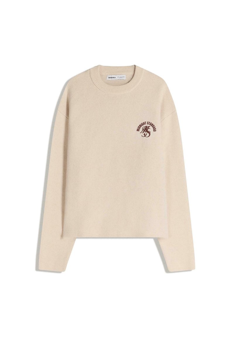 Béžový pletený svetr s kulatým výstřihem, spadlými rameny a malým vínovým logem na levé straně. Zkrácená délka.