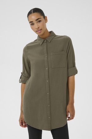 Olive green, button-up shirt with a collar, single chest pocket, and rolled sleeves. Made of soft fabric, featuring a rounded hem.