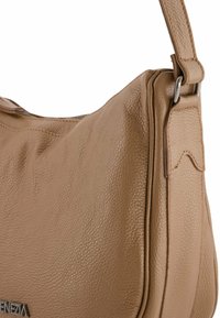 Tan leren schoudertas met een gestructureerd oppervlak, gekenmerkt door een gebogen vorm en een stevige band die is bevestigd met zilveren hardware accenten.