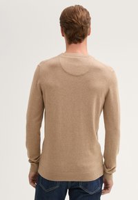 Lichtbruin gebreid sweater met een ronde hals, lange mouwen en een aansluitende tailleband. Gladde textuur en minimale stikdetails.