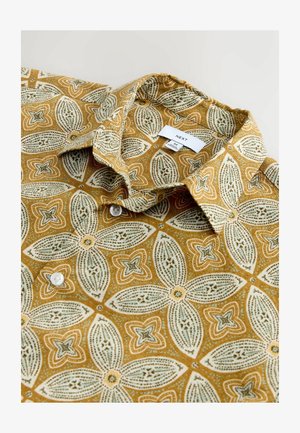 Kortærmet skjorte i sennepsgul med blomsterprint. Har krave og hvide knapper. Mærke placeret under kraven.