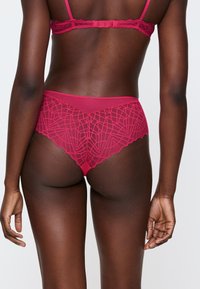 Fuksjowy zestaw bielizny koronkowej z geometrycznymi detalami, falbanką na majtkach oraz regulowaną ramiączką w biustonoszu.