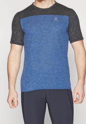 Hombre con camiseta deportiva de manga corta con torso azul jaspeado y mangas gris oscuro, combinada con leggings negros de entrenamiento.