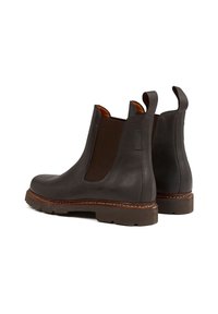 Bottines Chelsea en cuir brun avec des panneaux latéraux élastiques, bout rond et semelle en caoutchouc épaisse. Détails de couture contrastée sur le bord.