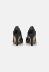 Svarta läderhögklackade skor med spetsig tå och smal stilettohæl. Slät textur med minimala sömmar baktill.