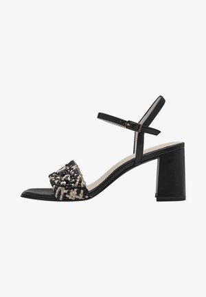 Sorte og beige vævet sandaler med blokhæl; har en ankle strap og en glat sort sål. Den teksturerede overdel giver detaljer.