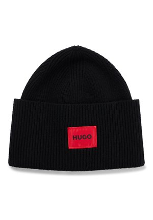 Sort ribstrikket hue med opbukket kant og en rød rektangulær mærkat med teksten "HUGO" centreret på kanten.