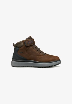 Botas de senderismo marrones de media caña con parte superior de cuero y tejido, cierre de cordones, cuello acolchado, suela de goma y correa ajustable con logo.
