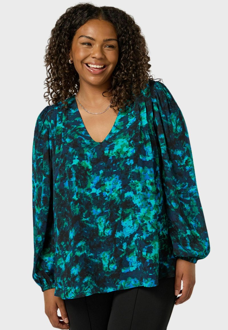 V-ringad blus i ett abstrakt mönster av svart, blått och grönt. Har långa ärmar med puffiga axlar. Lättviktsmaterial med en mjuk textur.