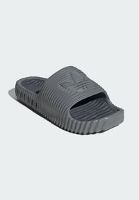Gray slide sandal made from rubber with a ridged design, open toe, and embossed logo on the strap, featuring a textured footbed for grip.