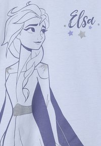 Hellblaues T-Shirt mit einem Grafikmotiv eines Charakters mit Zopf, eingerahmt in Dunkelviolett, akzentuiert mit silbernen Sternen und dem Text "Elsa".